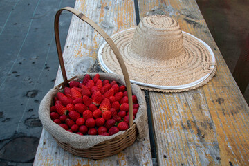Basket and spoon hat with strawberries evoke an irresistible rural charm: red fruits, wicker and straw in harmony, harvesting sweet memories in the countryside.
