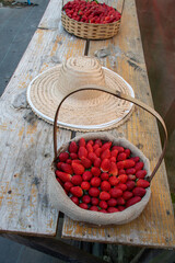 Basket and spoon hat with strawberries evoke an irresistible rural charm: red fruits, wicker and straw in harmony, harvesting sweet memories in the countryside.