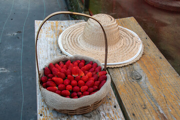 Basket and spoon hat with strawberries evoke an irresistible rural charm: red fruits, wicker and straw in harmony, harvesting sweet memories in the countryside.