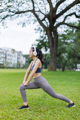 Portrait of a smiling young fitness asian girl doing stretching in the park.Healthy women exercise concept.
