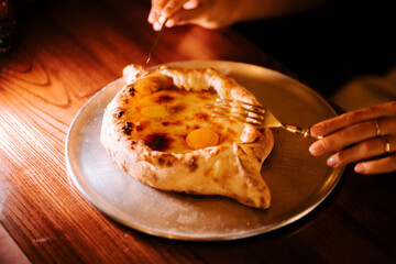 Enjoying traditional Adjarian khachapuri with eggs and cheese on a cozy evening