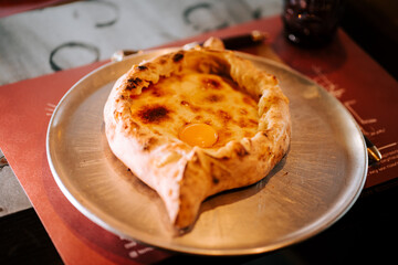 Delicious traditional Adjarian khachapuri served on a plate with a runny egg on top