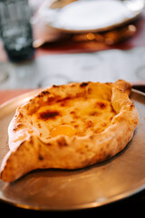 Enjoying traditional Adjarian khachapuri served fresh on a metal plate with rich cheese and egg