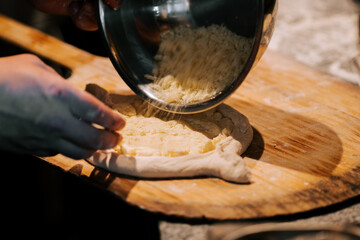Preparation of traditional Adjarian Khachapuri with melted cheese in a cozy kitchen setting