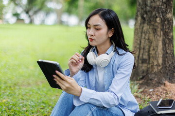 Obraz premium Young studying students asian woman sitting outdoors and reading a book enjoying leisure time in a park, copy space. Education studying students concept 