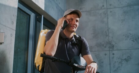 Delivery Man on E-Scooter Standing near Modern Office, Notifying Client about Successful Delivery...