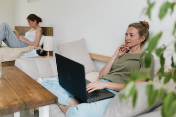 Middle age woman working on laptop at home, promoting active and healthy lifestyle with focus on wellbeing and fitness