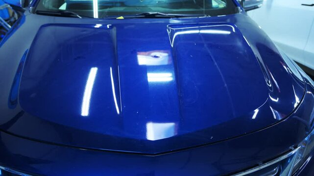 A car with severe hail damage sits inside an auto body repair shop. Process of PDR pointless dent repair on car body