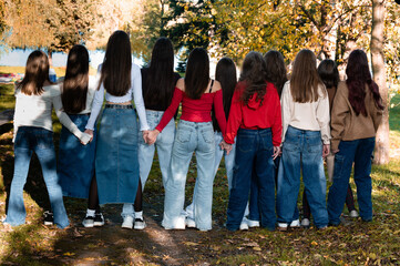 Group of girls holding hands, autumn park setting.