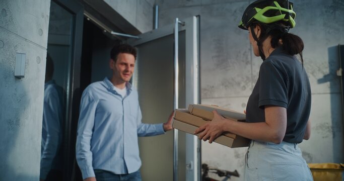 Woman Working in Pizza Delivery Service, Brining Restaurant Food for Client Working in Office Building. Businessman Taking Pizza in Cardboard Boxes, Paying for Order Contactless Using Smartphone.