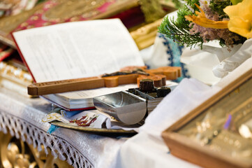 Religious ceremony items: open book, wooden cross, and a metal container.