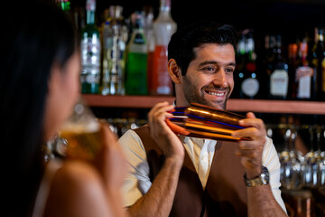 A charismatic bartender or mixologist smiles at a customer while preparing a craft cocktail with a shaker A concept for the hospitality industry and expert service