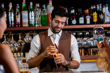 A charismatic bartender or mixologist smiles at a customer while preparing a craft cocktail with a shaker A concept for the hospitality industry and expert service