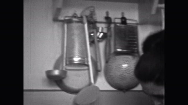 Vintage film, Woman in kitchen cooking food, black white archival. Mother preparing meat meal for family at home. Kitchen utensils. Classic housewife in retro 1960s archive. Homemaker in archives