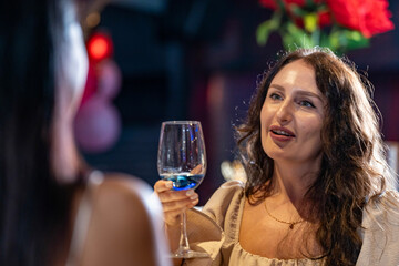 Two female friends enjoy a deep conversation over a glass of wine at a party or bar A concept for...
