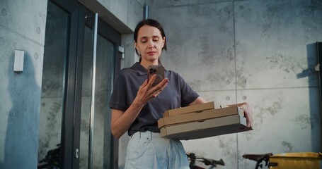 Delivery Woman Standing near Office Building with Pizza in Cardboard Boxes, Notifying Client by Phone about Successful Delivery. Woman Working in Pizza Delivery Service, Delivering Restaurant Food.
