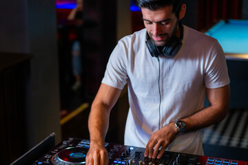 A professional DJ mixes a live set on a controller in a dark nightclub or bar A concept for...