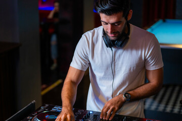 A professional DJ mixes a live set on a controller in a dark nightclub or bar A concept for...
