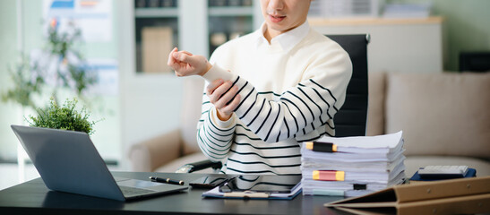 Overworked young Asian businessman office worker suffering from neck pain after had a long day at...