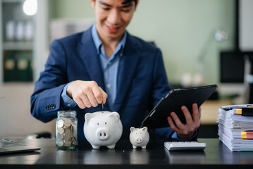 Smiling businessman saves money with piggy bank and coins; ideal for themes of finance, savings,...