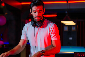 A professional DJ mixes a live set on a controller in a dark nightclub or bar A concept for...