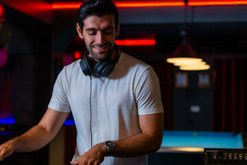 A professional DJ mixes a live set on a controller in a dark nightclub or bar A concept for...