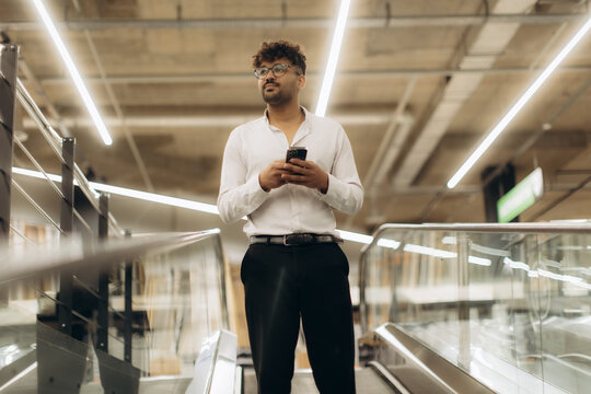 Confident Businessman Using Smartphone While Standing in a Modern Workplace - Powered by Adobe