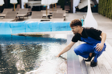 Pool maintenance worker checking water quality in swimming pool