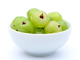 A close-up of fresh, vibrant green Amla gooseberries artfully arranged in a pristine white ceramic bowl, showcasing their natural beauty and potential health benefits on a clean white background