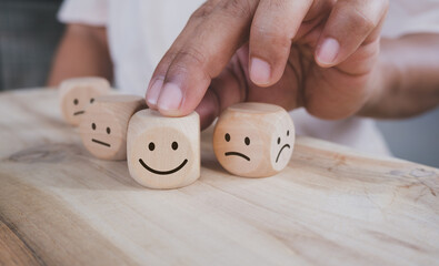 Hand holding wood cube with smile icon, World mental health day or feedback rating concept, Positive customer review, Wood cube stacking with emotion face icon on wood background
