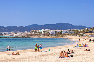 Sunbathing people on a beach by the mediterranean sea at a resort in Mallorca