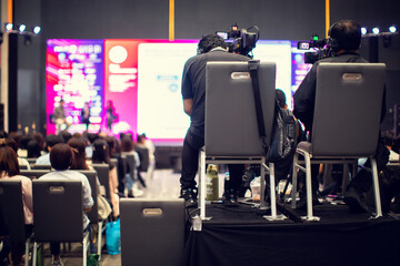 selective focus to cameraman with blurry video camera set are recording to speaker and audience in conference hall or seminar event. exhibition convention center.