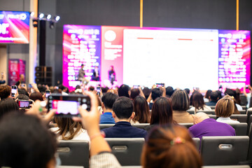 Selective focus to audience with blurry the cameraman and video camera set to recording the speaker and audience in conference hall or seminar event. exhibition convention center.