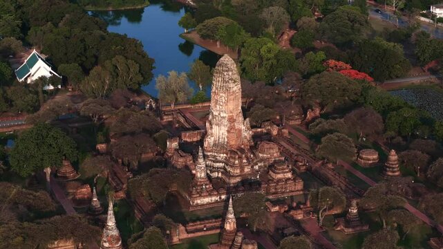Close orbit aerial motion of Wat Phra Ram ruins showing detailed prang and ancient brick structures at sunset