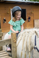 Little toddler girl riding a horse pony, kids and animals