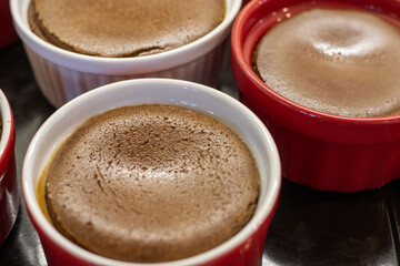 Freshly baked chocolate cheesecakes in red and white ramekins