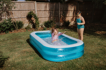 Siblings playing in inflatable backyard pool © Cavan