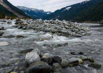 Mountain river flows over smooth stones in a serene valley