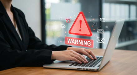 Cybersecurity Alert: A focused professional works on a laptop, with a warning sign highlighting potential digital risks and threats