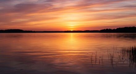 Fototapeta premium Fiery sunset over tranquil lake reflecting vibrant orange and pink hues
