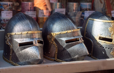 Three helmets are on display, one of which is gold and silver