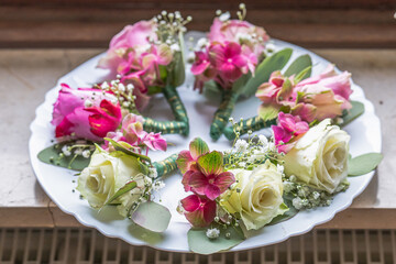 Small stylish boutonnieres on white marble plate, flat lay colorful many groom