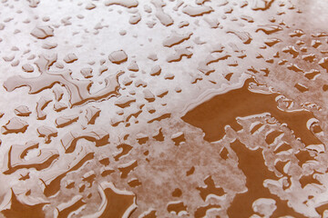 A brown surface with water droplets scattered all over it