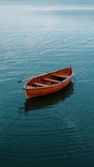 Naklejka premium Minimalist Aerial View of Red Wooden Rowboat Floating in Calm Deep Blue Water with Gentle Ripples