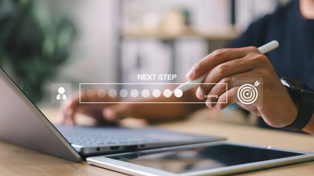 Businessman interacting with digital progress bar and “Next Step” interface on laptop and tablet. Concept of business development, decision making, and digital process.