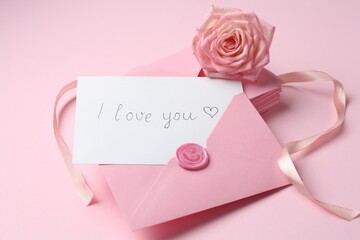 Stack of letters, card with phrase I Love You and rose flower on pink background, closeup