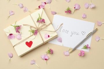 Stack of letters, card with phrase I Love You, pen and flowers on beige background, flat lay