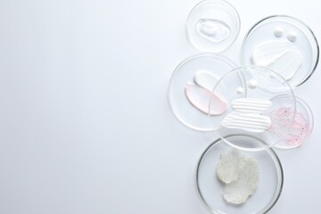 Different cosmetic products in Petri dishes on white background, flat lay. Space for text