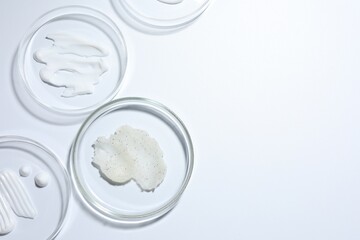 Different cosmetic products in Petri dishes on white background, flat lay. Space for text
