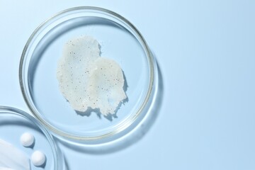 Different cosmetic products in Petri dishes on light blue background, flat lay. Space for text